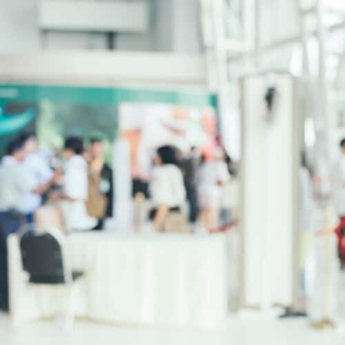 Bokeh blurry image of the entrance to an exhibition hall showing a small exhibition stand area