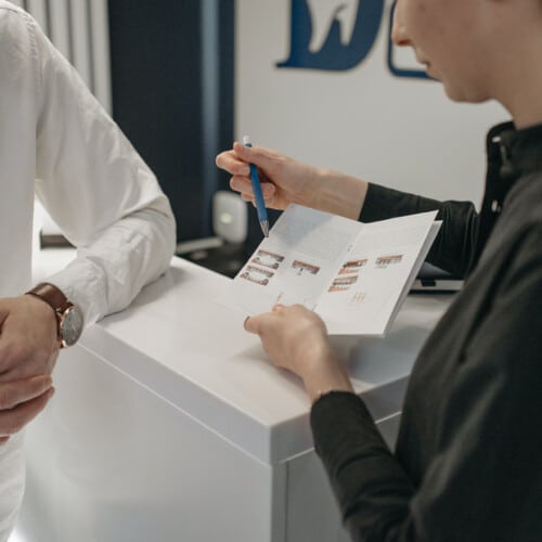 woman talking through the contents of a brochure with a man who is leaning on a counter image by Pavel Danilyuk on pexels.com